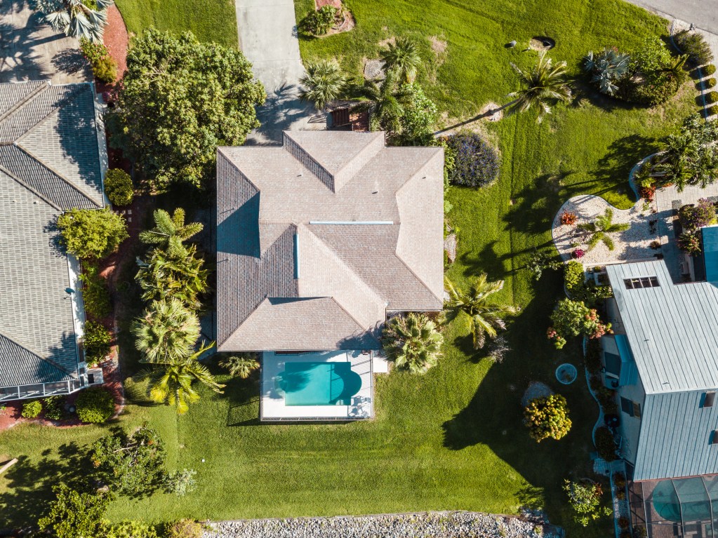 Aerial view of a Florida residential property illustrating landscape design in Florida, including roof layout, lawn areas, trees, and surrounding site context.